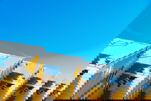 A row of yellow and white buildings showcasing Rotterdam's architecture against the backdrop of a blue sky in The Netherlands.