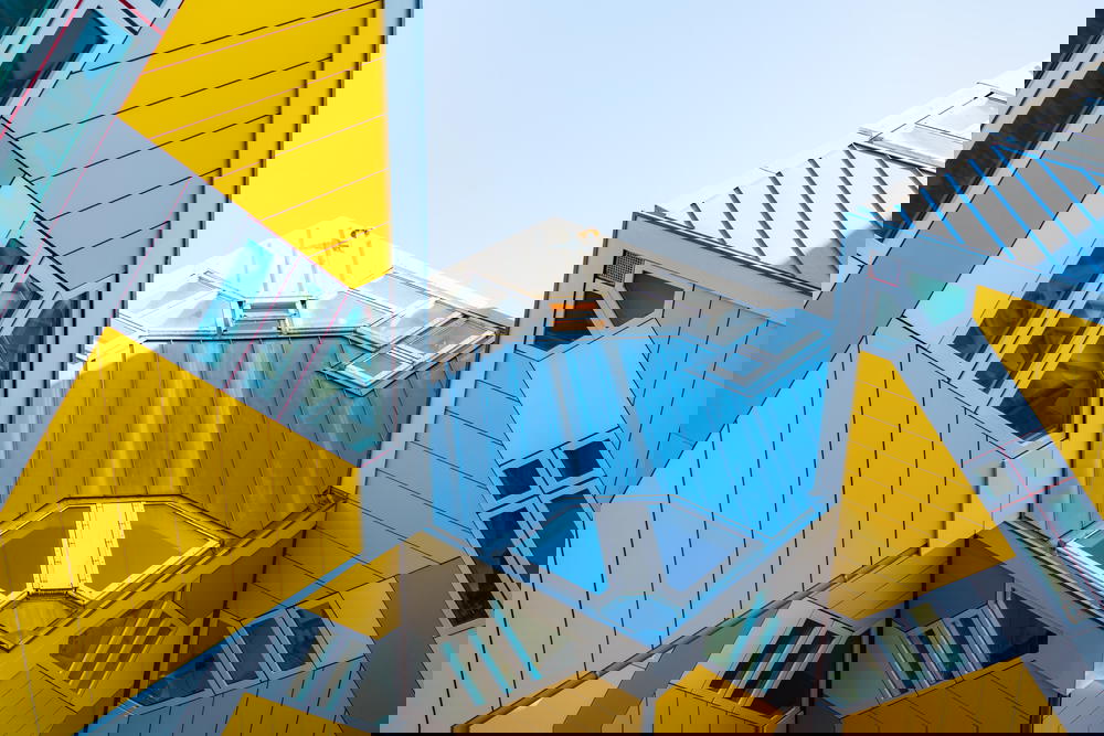 A group of yellow and gray buildings showcasing Rotterdam's architecture against a vibrant blue sky.