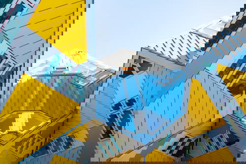 A group of yellow and gray buildings showcasing Rotterdam's architecture against a vibrant blue sky.