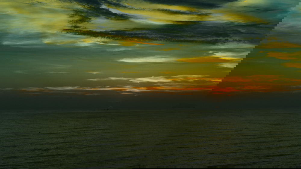 A person is flying a kite over the ocean in Peru at sunset.