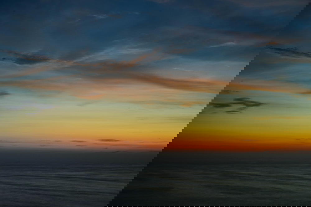 A sunset over the ocean with a boat in the background in Peru.