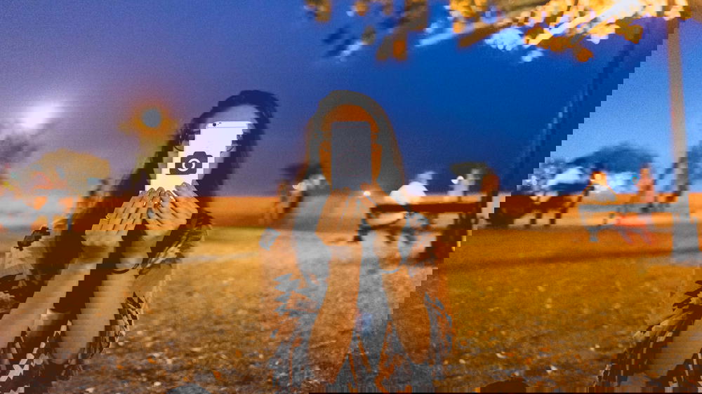 A woman taking a selfie with her phone in a park at night in Peru.