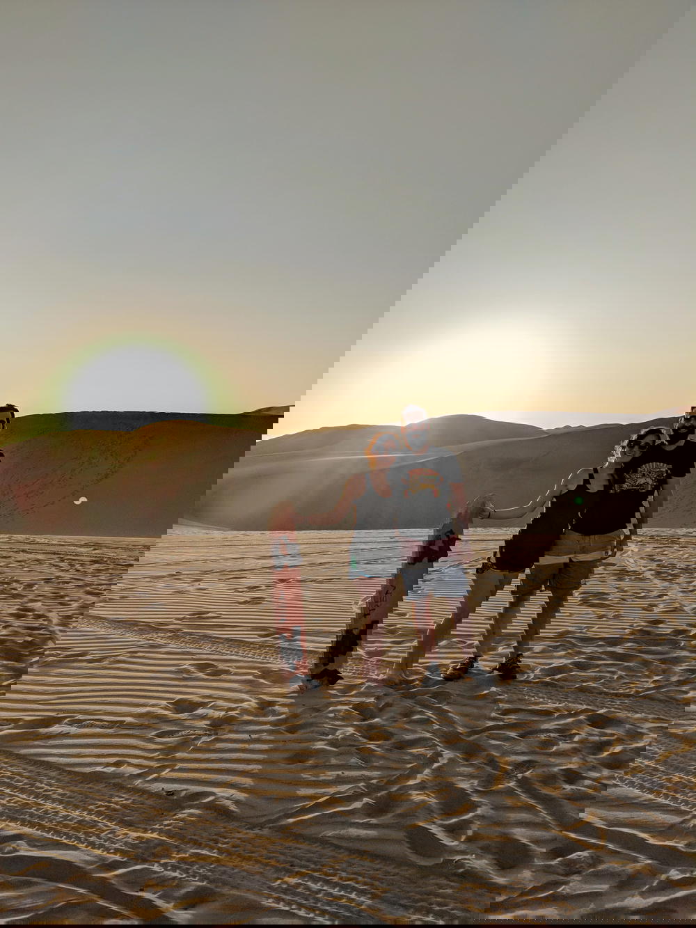 Couple smiling with sandboards before sunset in desert