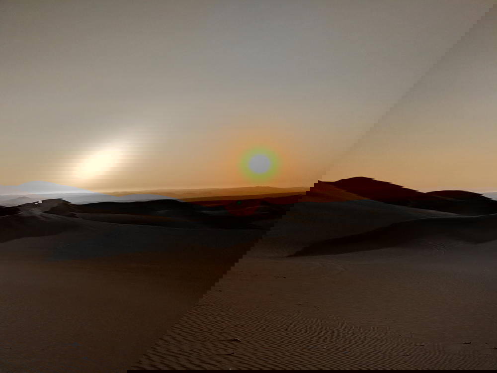 Beautiful sunset scene with sun going down behind sand dunes