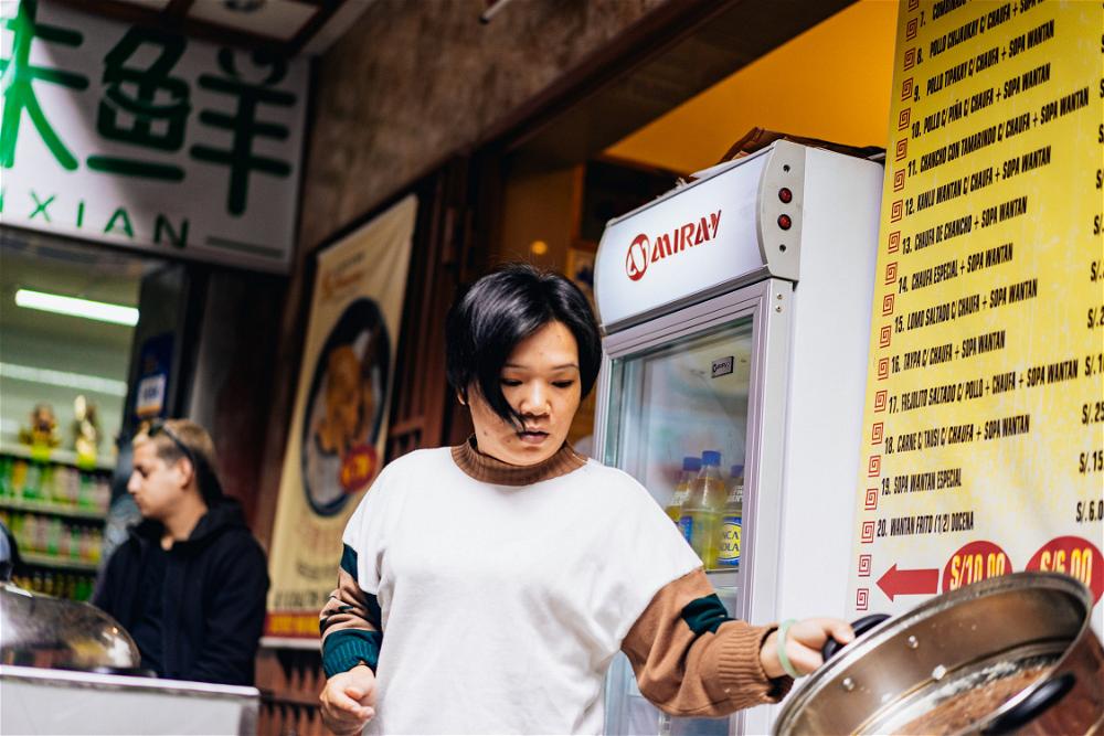 Woman in Lima's Chinatown Barrio Chino making Chaufa food in a metal pot
