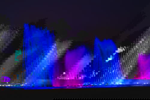 Huge park fountain shooting vertical streams of water for a water and light show at night