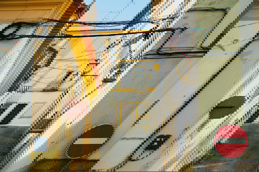 A narrow alleyway in Portugal adorned with a sign and wires.