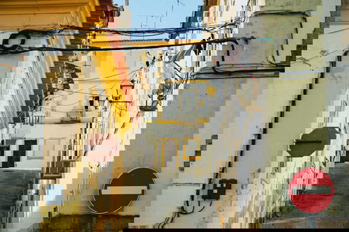 A narrow alleyway in Portugal adorned with a sign and wires.