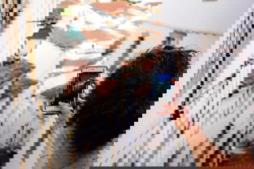 Women holding up a cell phone to take a photo of depth in a Portuguese village of white houses