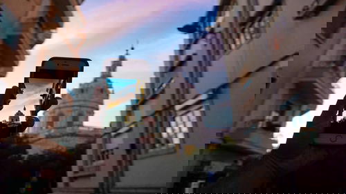 A person holding up a cell phone with a picture of a church in Portugal in the background.