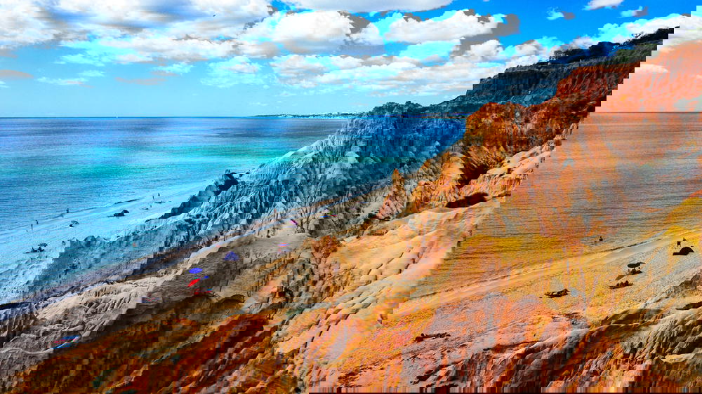 A Portugal beach with cliffs and a blue sky.