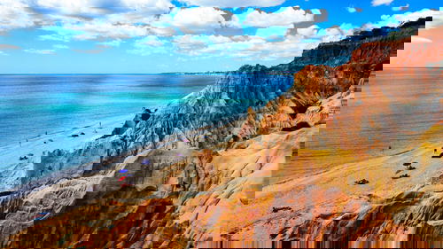 A Portugal beach with cliffs and a blue sky.