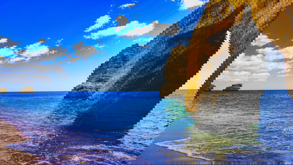 A beach in Portugal with cliffs and a blue sky.