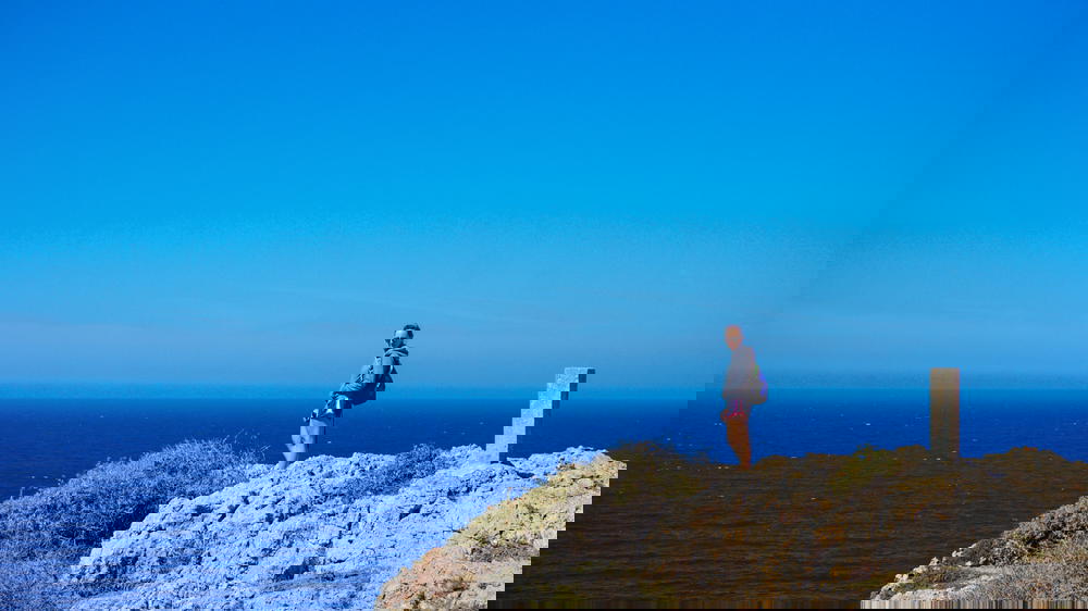 A person standing on a cliff in Portugal overlooking the ocean.