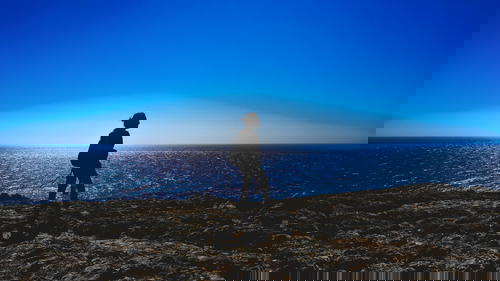 A silhouette of a man standing on top of a cliff overlooking the ocean in Portugal.