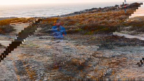 A woman is walking down a path near the ocean in Portugal.