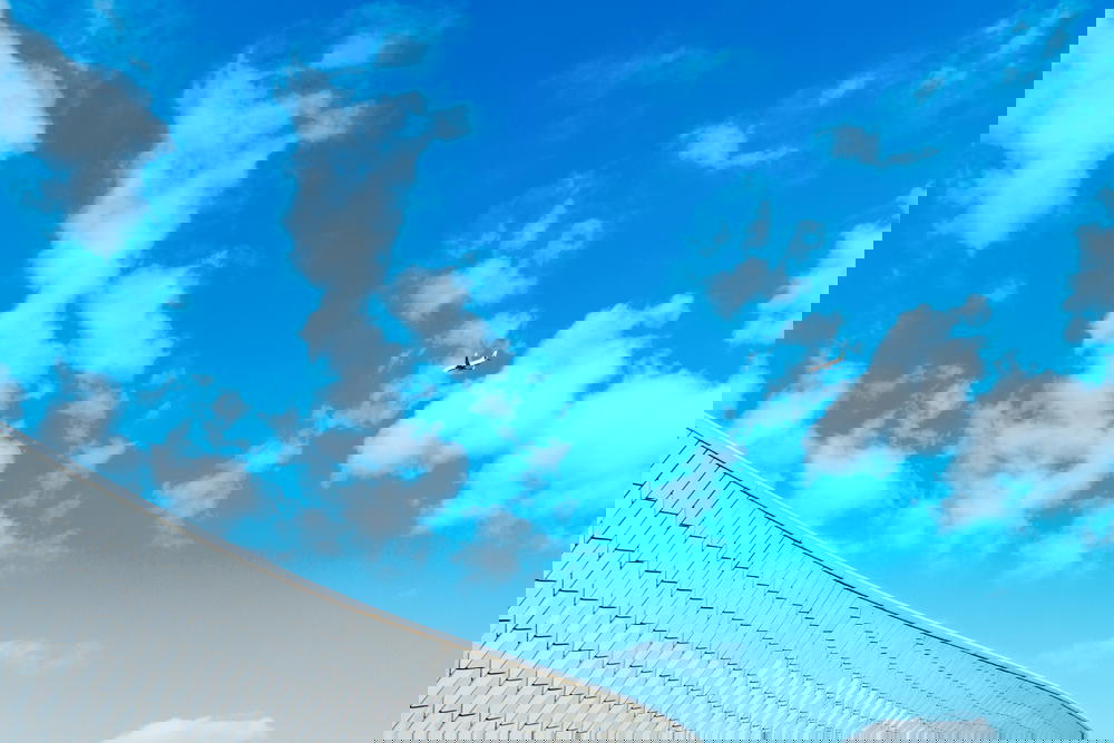 Wavelike wall of the maat museum against a blue sky with clouds