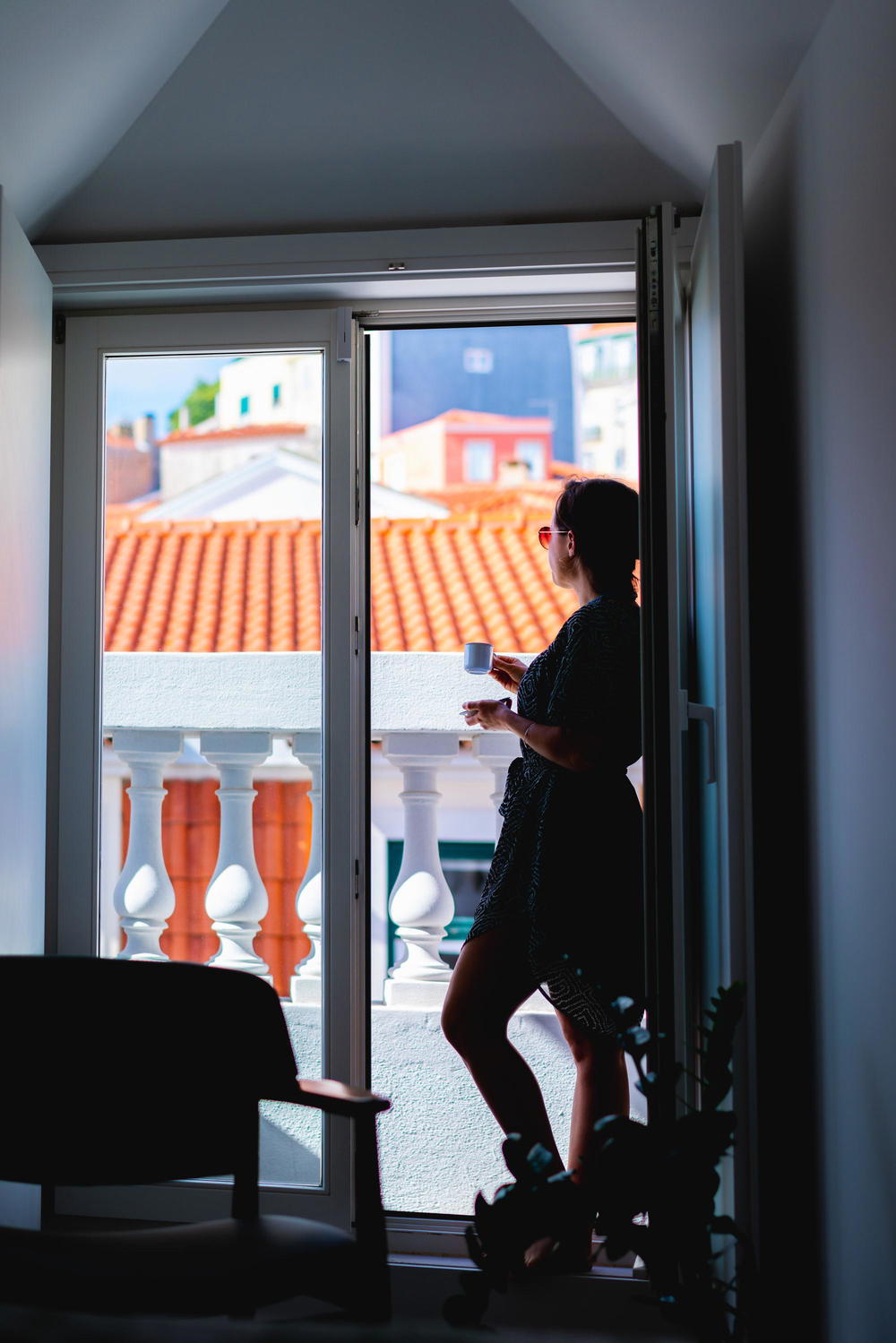 Woman drinking tea while looking out a window at The Lisboans in Lisbon, Portugal