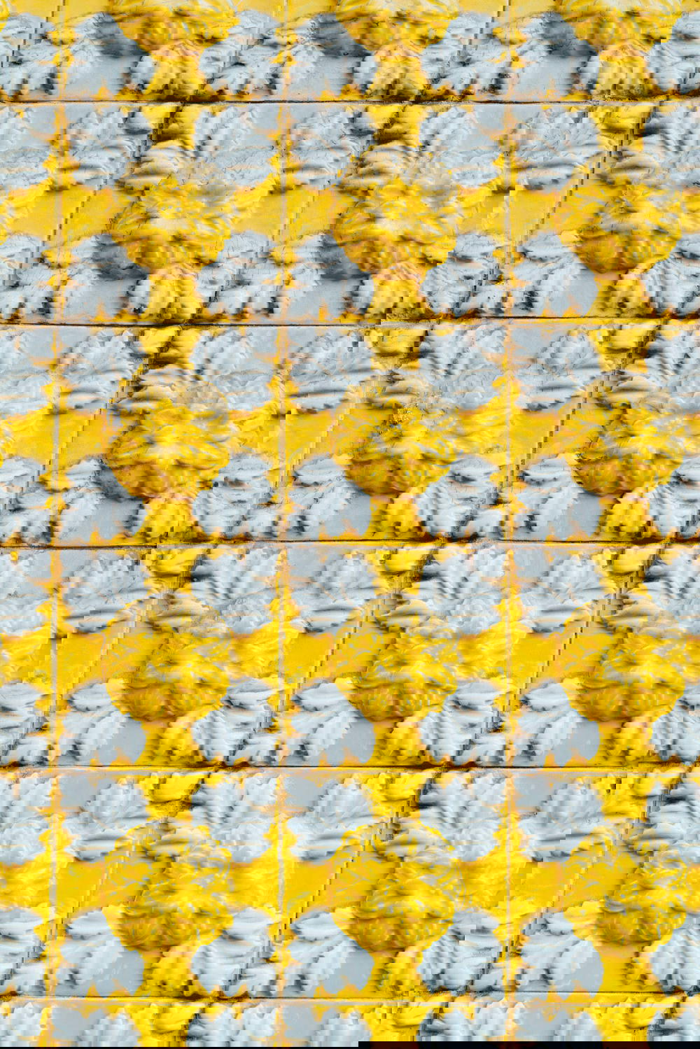 A yellow tile from Porto, Portugal featuring white flowers.