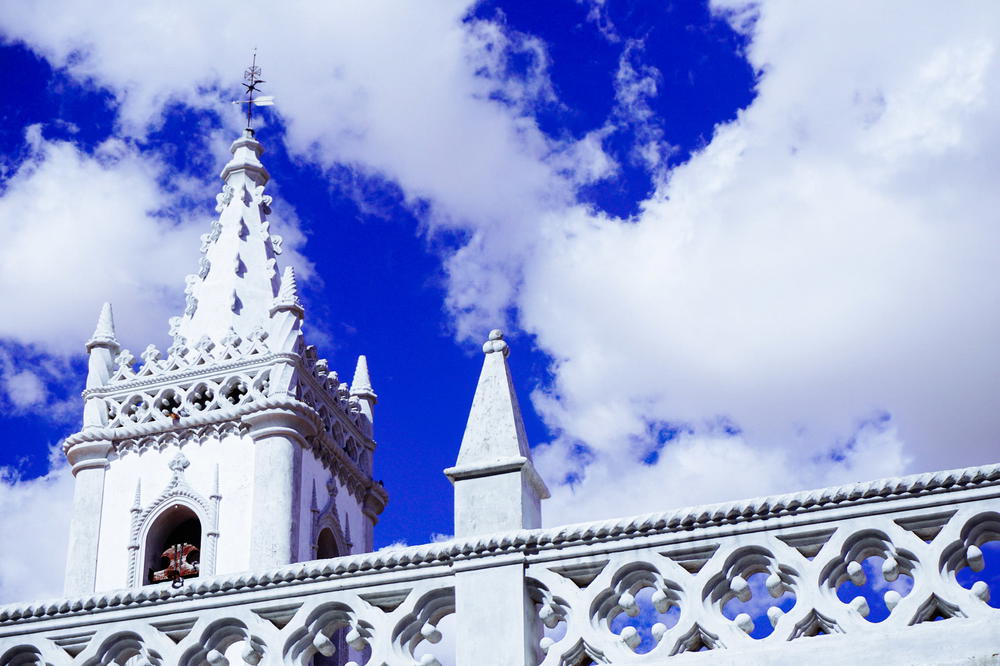 A white building with a clock tower, set against a vivid blue sky in Portugal.