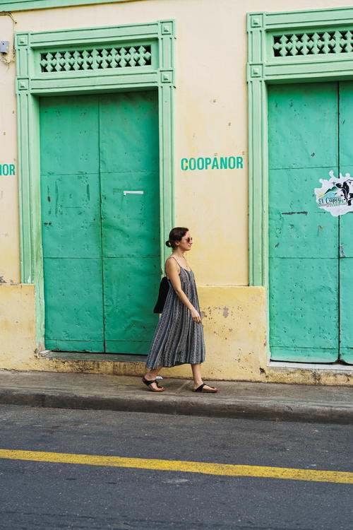 Woman walking past pastel colored walls and doors in historic center of Puerto Plata city Dominican Republic