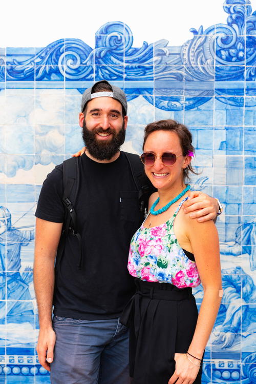 A man and a woman posing for a picture in front of a blue tiled wall.