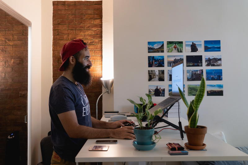 A man sitting at a desk with a plant in front of him.