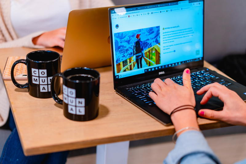 A woman typing on a laptop while sitting at a table.