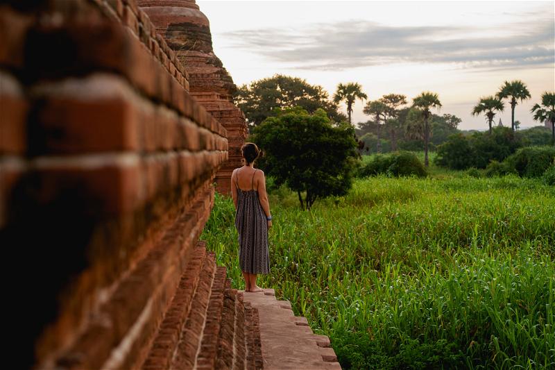 A woman is standing on a brick wall.