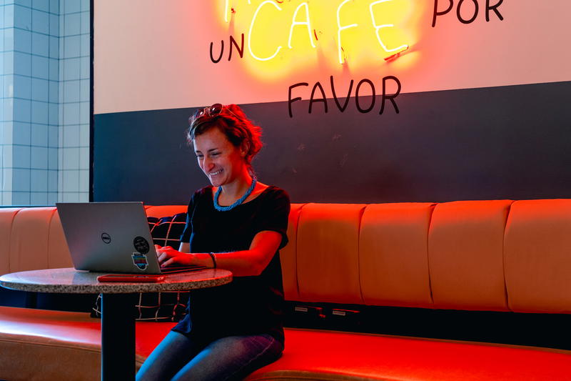 A woman sitting on a bench with a laptop.