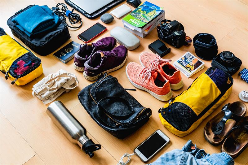 The contents of a travel bag are laid out on a wooden floor.