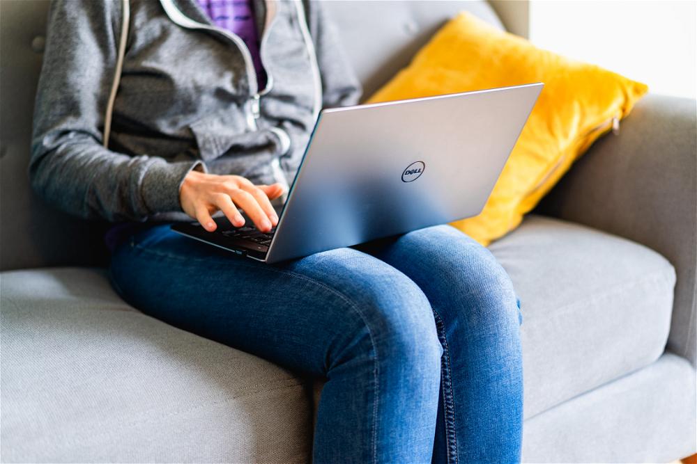 A woman sitting on a couch with a laptop.