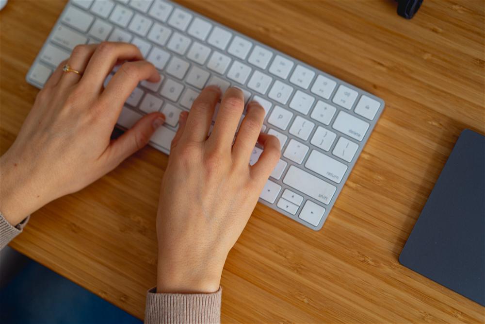 Woman typing on an Apple Magic keyboard