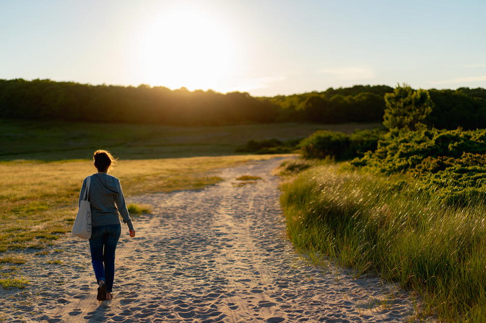 Women wearing an aviator first class travel hoodie walking through a beach at sunset.