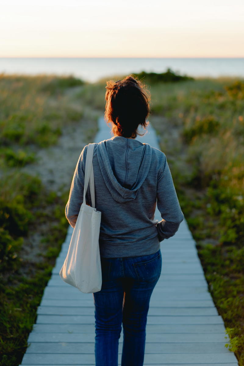 Women wearing an aviator first class travel hoodie walking on a deck near the ocean.