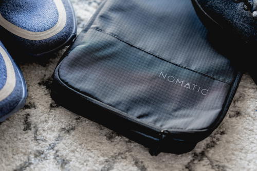 Nomatic shoe bag with two pairs of shoes close by.
