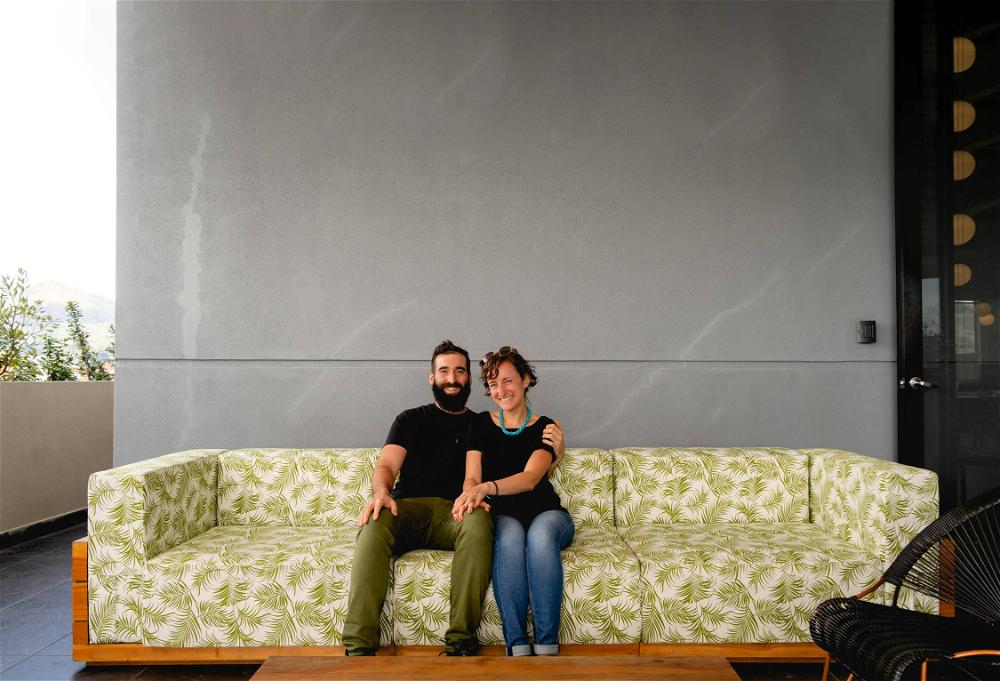 A man and woman sitting on a green couch.