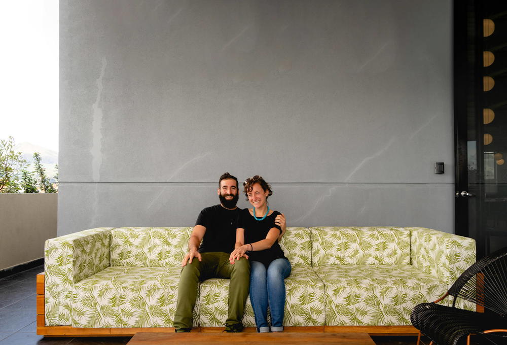 A man and woman sitting on a green couch.