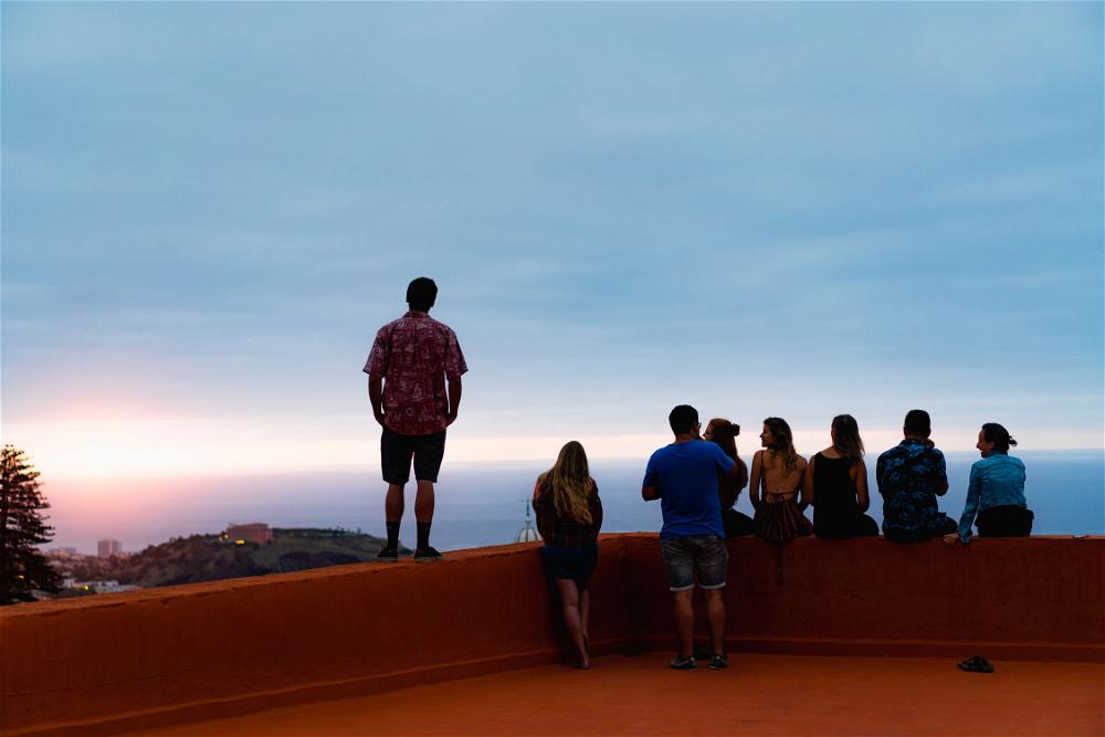 A group of people standing on a ledge overlooking the ocean.