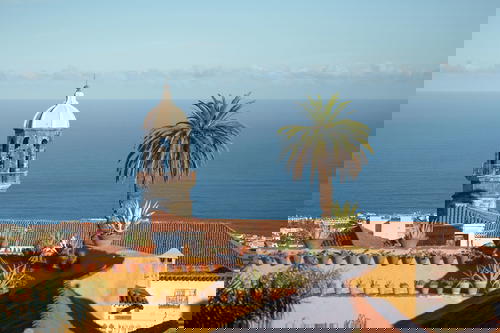 A building with a clock tower and palm trees.