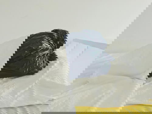 A bed with a black garbage bag on top of it.