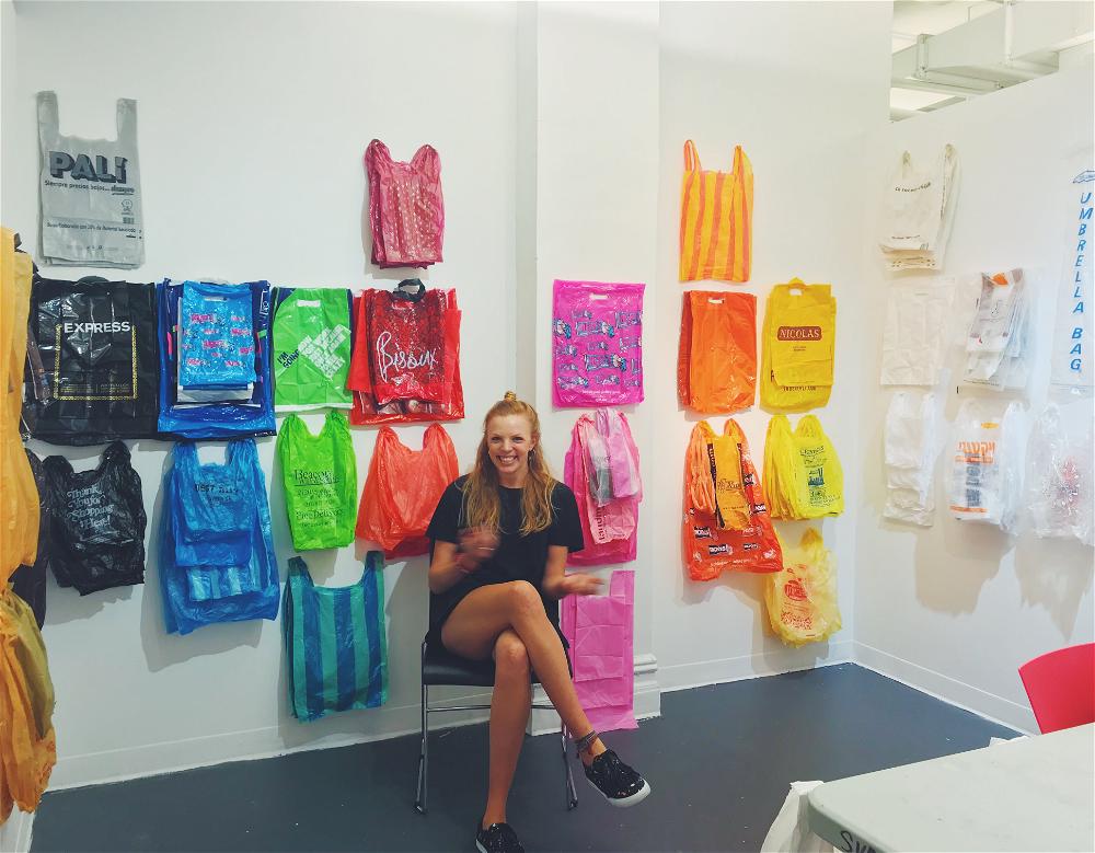 A woman sitting in front of a wall of plastic bags.