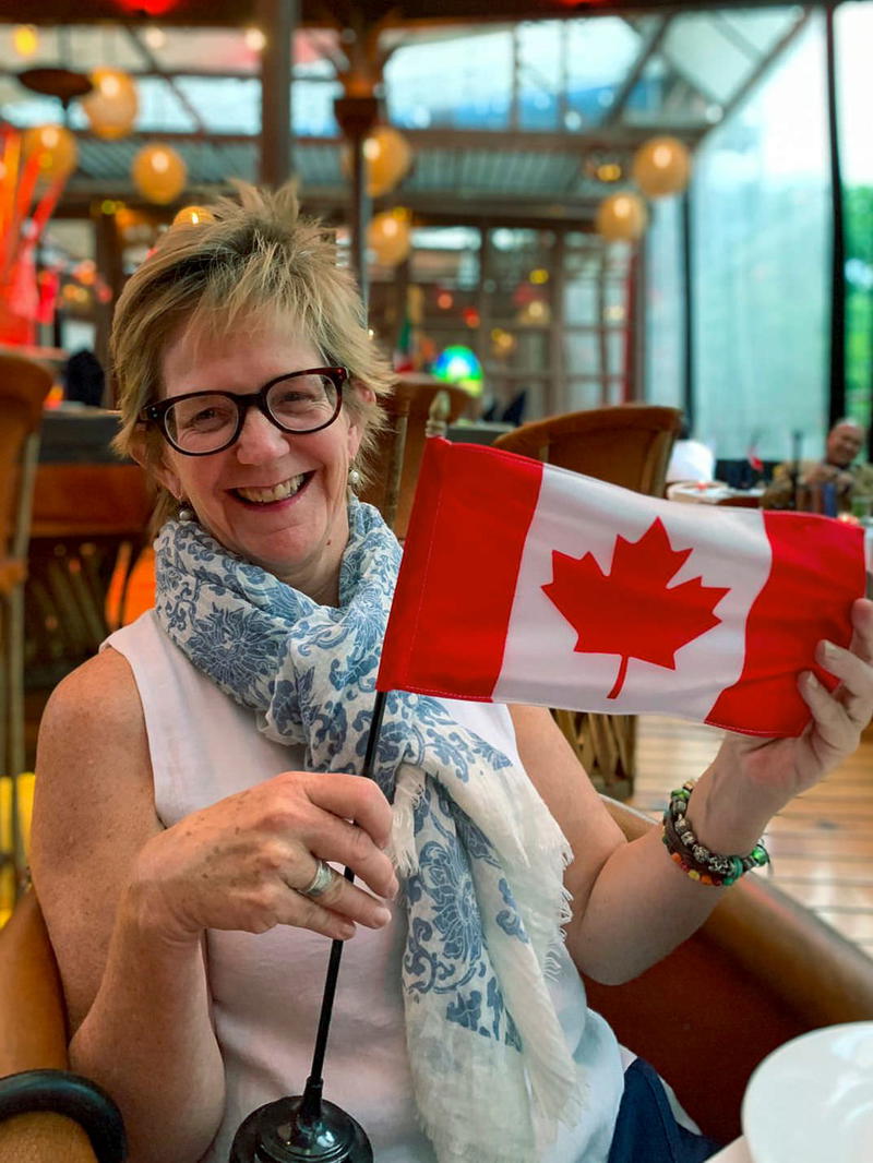 a woman sitting at a table holding a canadian flag