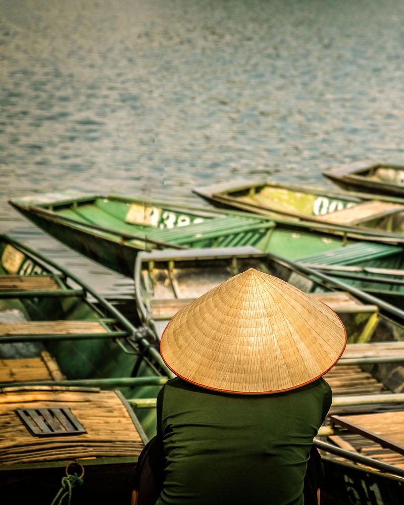 a woman in a hat sitting on a dock next to boats