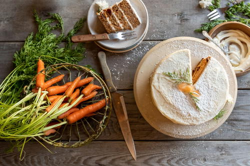 a wooden table topped with carrots and a cake