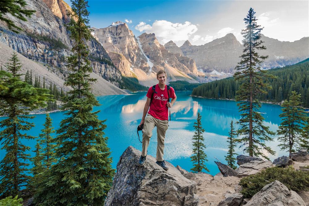 A man standing on a rock next to a lake in banff national park.