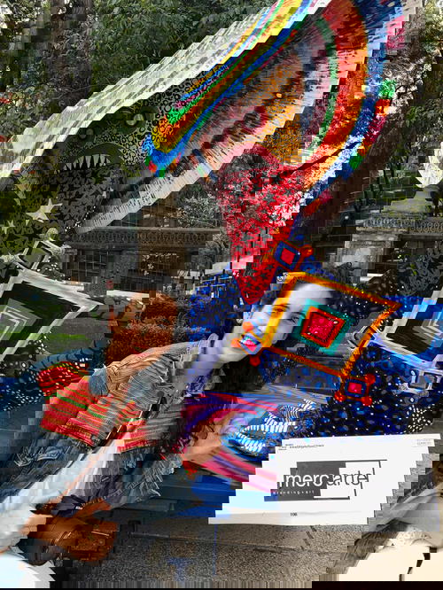 A woman is posing next to a colorful mexican sculpture.