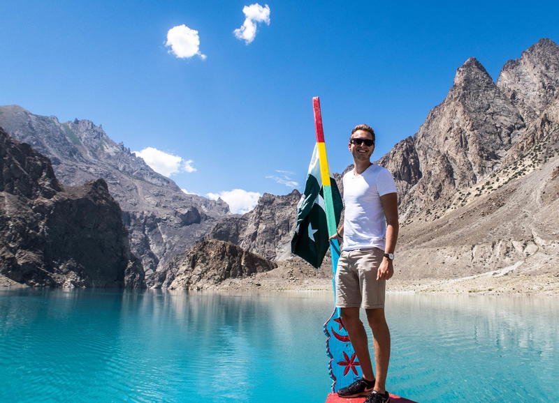 A man standing on top of a paddle board in front of mountains.