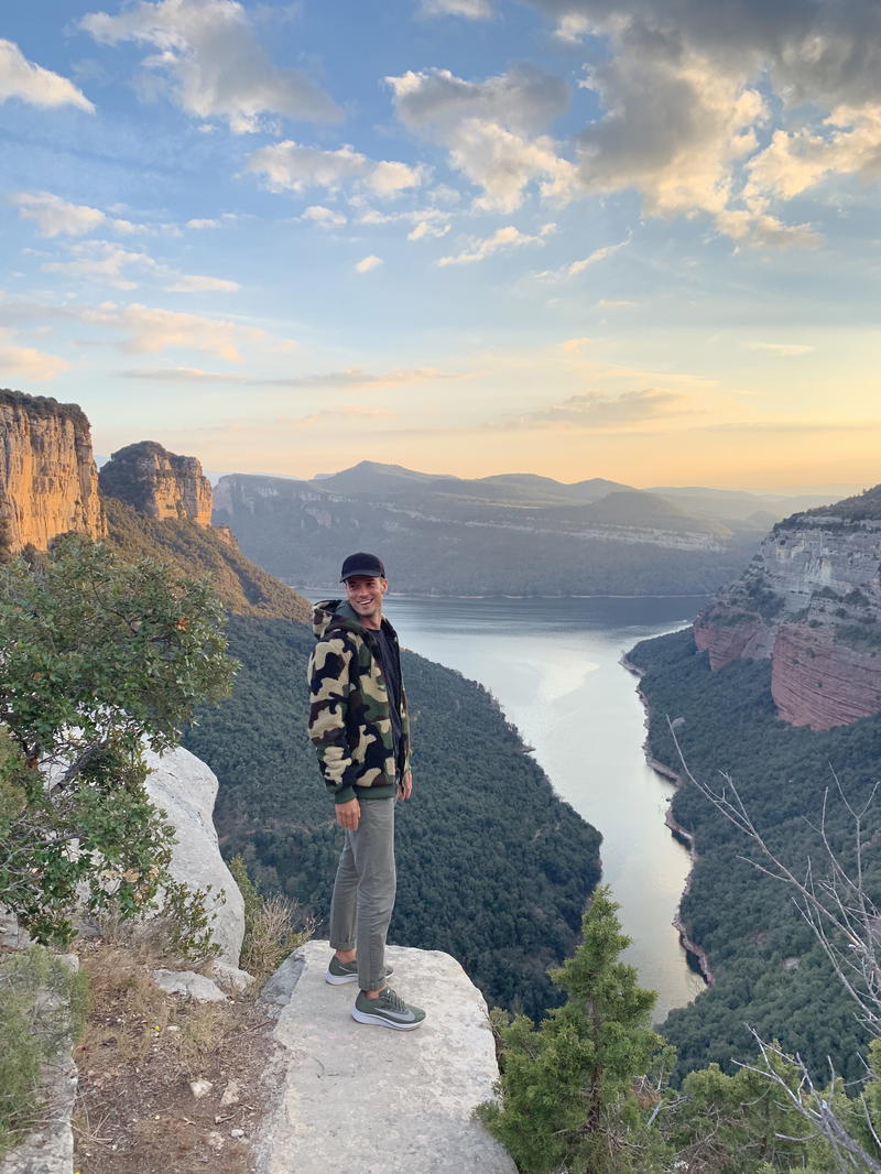 A man standing on a cliff overlooking a lake.