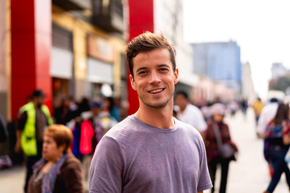 A young man standing on a street in a city.